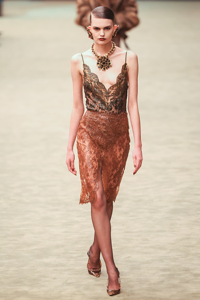 Aubria Abell walked the Saint Laurent Womenswear Fall/Winter 2026-2027 runway in a black sheer spaghetti strap bustier camisole bodysuit and a high-waisted burnt orange sheer thigh-high split midi pencil skirt.