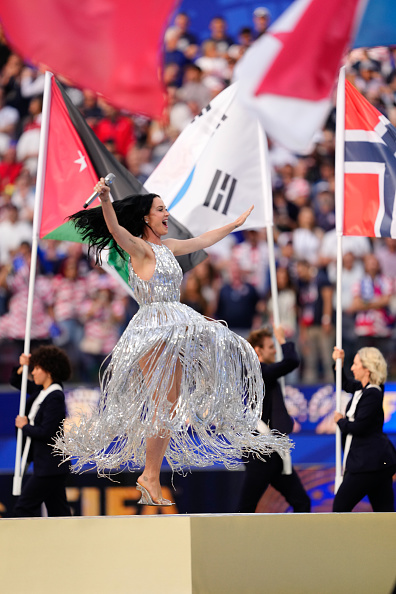 At the 2026 FIFA World Cup Los Angeles Opening Ceremony, Katy Perry performed wearing a silver Stella McCartney Fall/Winter 2026–2027 “Tinsel Lattice” fringe gown, paired with Aquazzura “Sea Wave” mules and Rainbow K “Nano Magnetic” earrings.