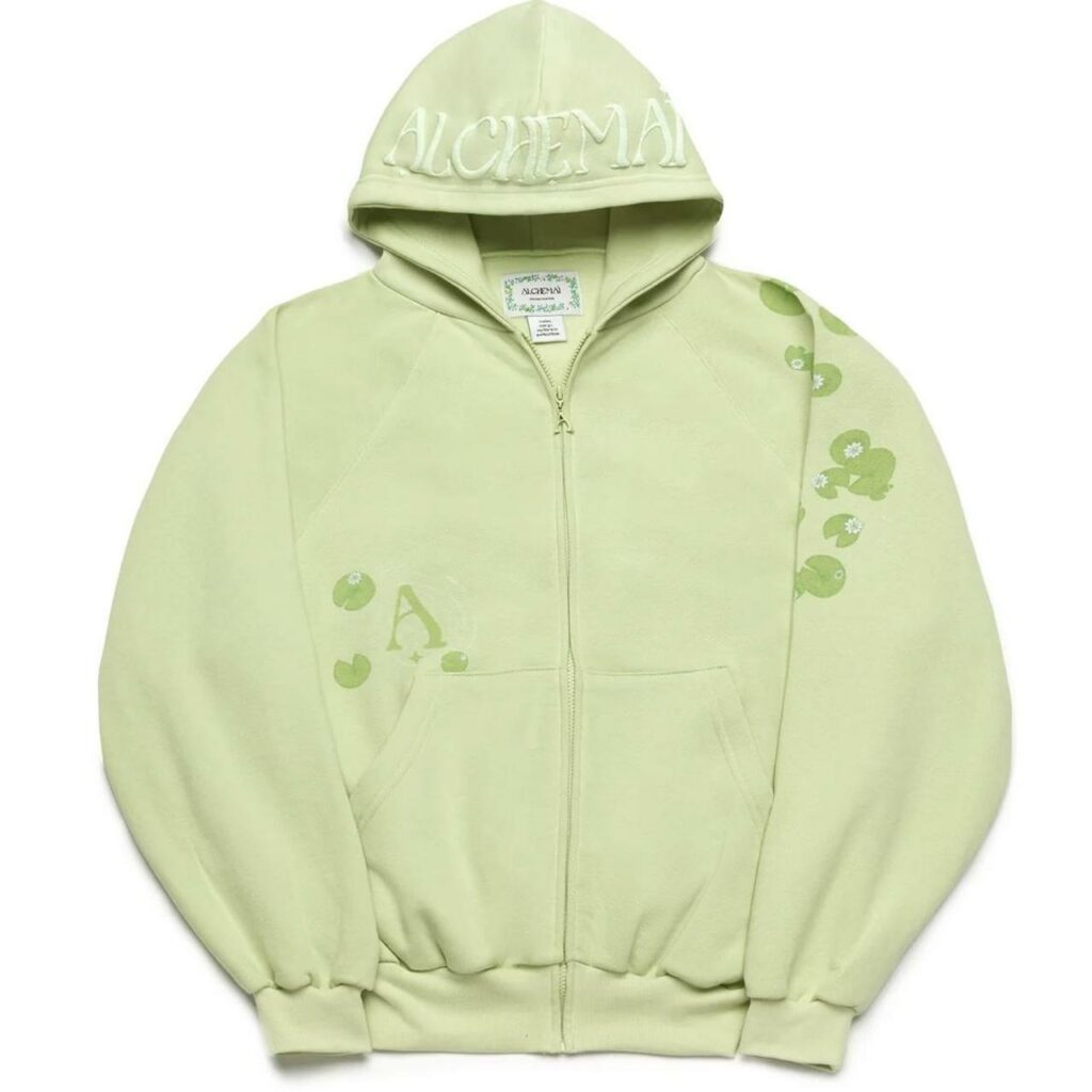 Light pastel-green zip-up hoodie with a hood and front pockets, featuring a subtle floral print along the right sleeve and ribbed cuffs.