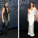 Two women on a red-carpet backdrop: left in a sleeveless black gown with a plunging neckline and fringe, right in a white one-shoulder dress with large cream and blue floral embellishment.