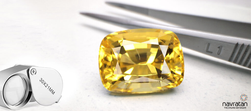 Yellow Sapphire stone next to tweezers and magnifier
