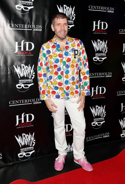 Perez Hilton teamed long trousers with a zip-up smiley face graphic design pattern print, not to mention his bright pink sneakers.