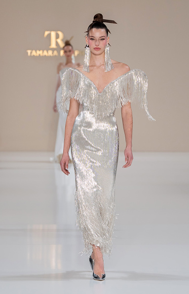 Karlijn Kusters walked the runway for Tamara Ralph Haute Couture’s Spring/Summer 2026 “La Lumière Dorée” collection in a silver bugle-bead fringe gown embellished with silver crystal xilions and finished with a dramatic wing neckline—reminiscent of the look Florence Pugh wore to the UK premiere of “Spider-Man: Brand New Day.”