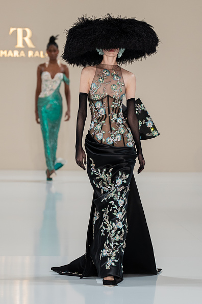 Tamara Ralph Haute Couture’s Spring/Summer 2026 “La Lumière Dorée” collection featured a black silk double-satin draped gown embellished with crystal silk floral embroidery, styled with a black ostrich-feather dome hat