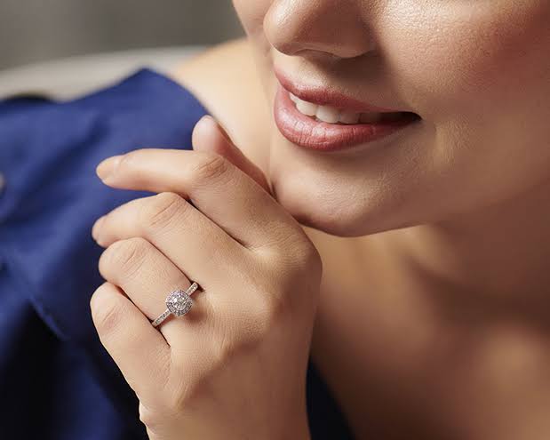 Close-up of a woman's hand resting by her chin, showing a diamond jewelry engagement ring.