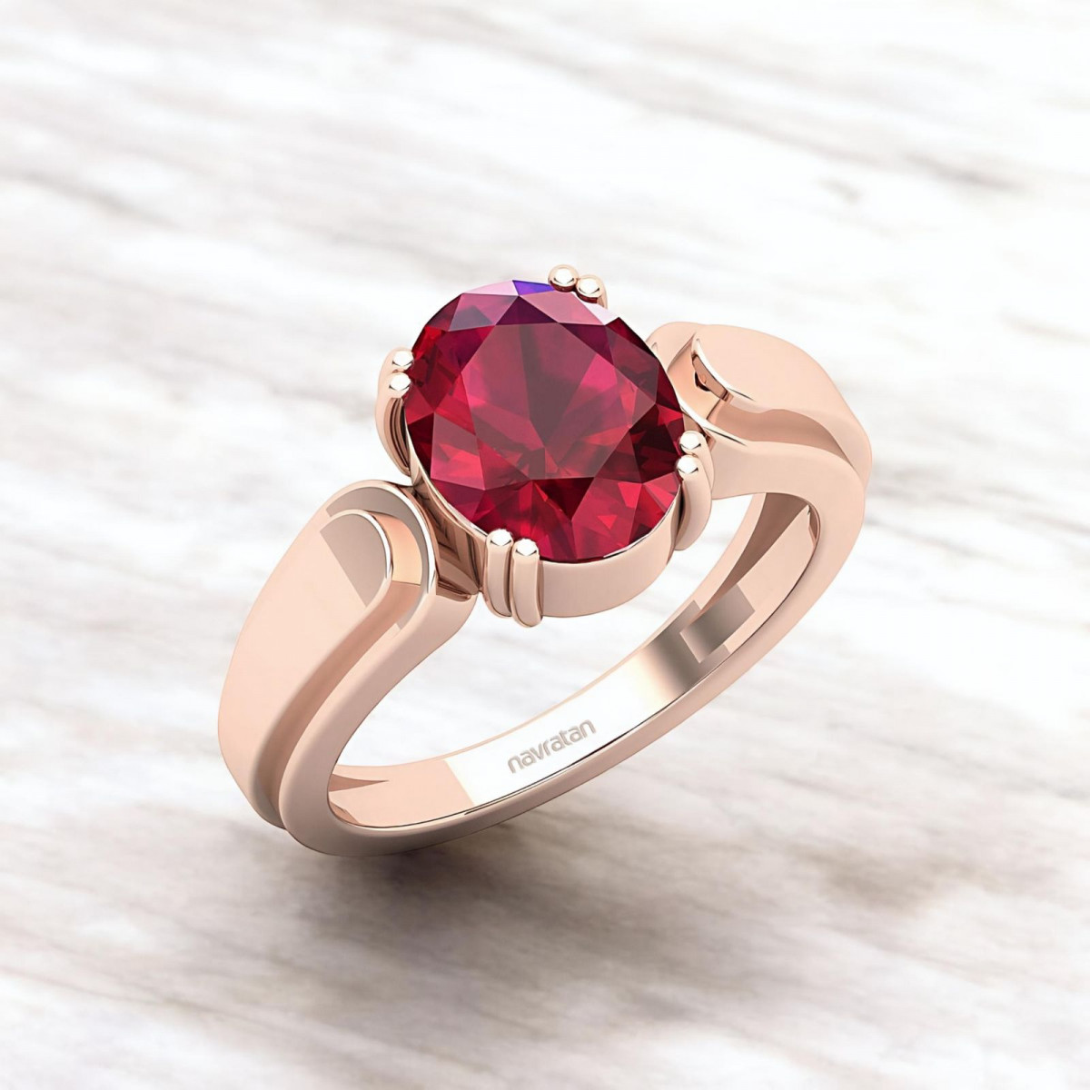 Rose gold ring featuring a round ruby stone set in a decorative prong setting on a light marble background.