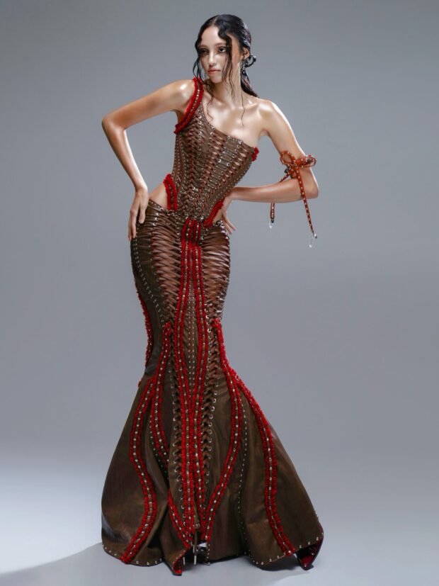 ManMadeSkins’ (MMS) Spring/Summer 2026 collection featured the “Crimson Thorn” ceremonial ensemble: a two-piece cutout lace-up corset bodysuit paired with a matching mermaid-style floor-length skirt, both crafted from premium cocoa-brown vegan leather.