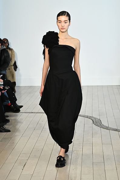 Ashlynn Park’s Fall/Winter 2026 collection featured a black “Evelin” virgin-wool dress, defined by its ruffled one-shoulder corsage, sculpted bodice, and asymmetrical cocoon-draped midi skirt
