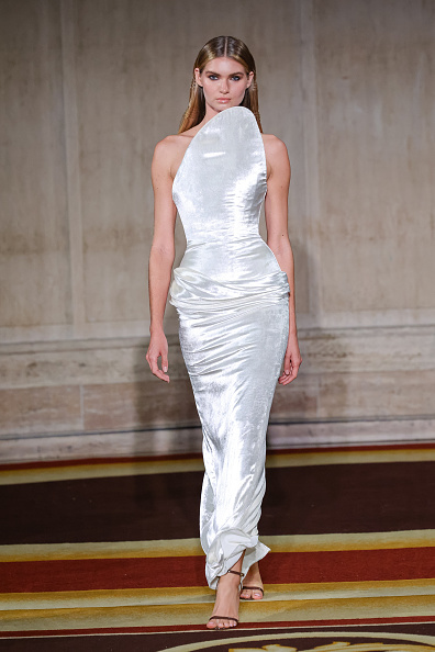 Christian Siriano’s Spring/Summer 2027 collection included a white crushed-velvet column maxi dress with an upward-sweeping asymmetric neckline, ruching, and a back slit