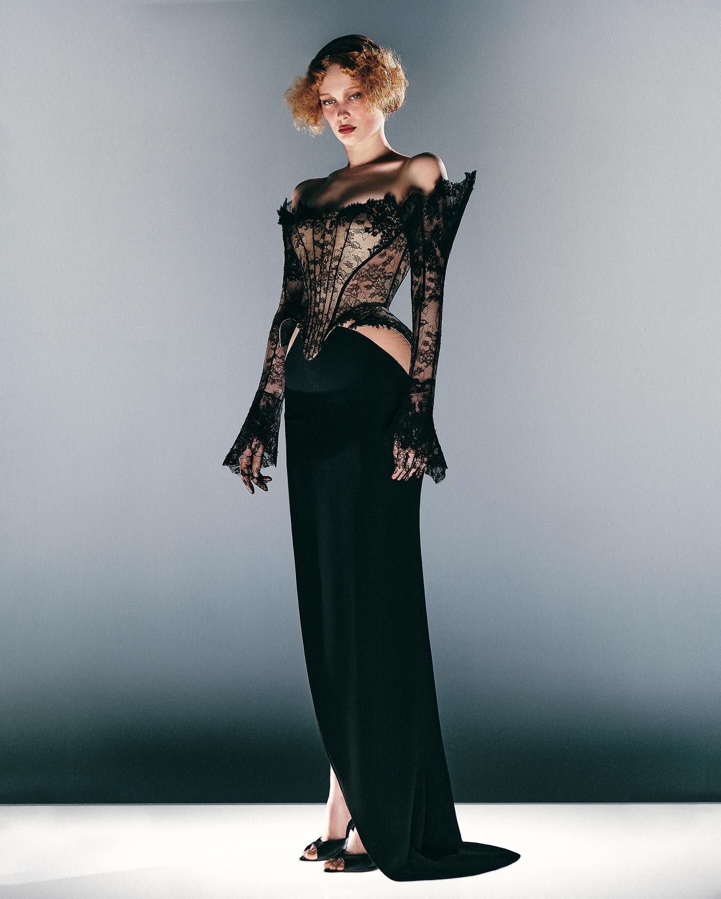 Belik’s 2025 collection showcased a long-sleeved gown featuring an off-the-shoulder lace corset decorated with intricate floral embroidery, hip cutouts, and a floor-length skirt finished with an ultra-high side slit