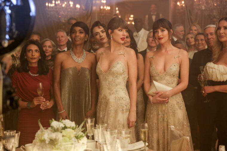 Taylor Swift was seen filming her latest music video, “Patient Zero,” wearing a nude Valentino gown with a sweetheart V-neck, floral embroidery, bow-detailed spaghetti straps, and a high-low tulle skirt.
