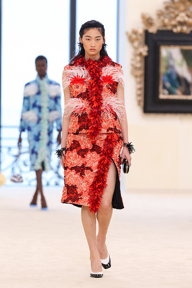 Chinese model Xiuli Jiang walks the runway at Chanel’s Cruise 2026/2027 ready-to-wear show in a two-tone ensemble featuring a sleeveless mock-neck top and knee-length pencil skirt accented by a thigh-high slit.