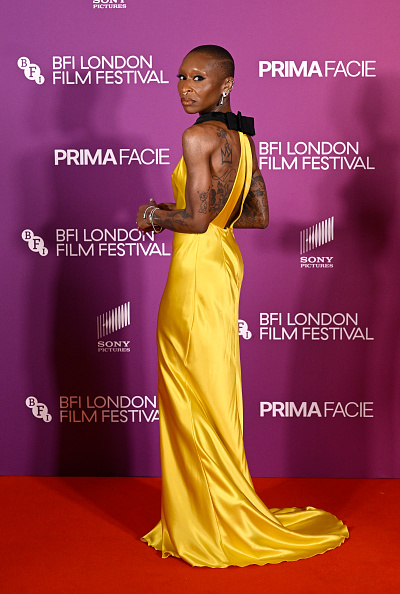 Cynthia Erivo attended the “Prima Facie” gala on the seventh day of the 70th BFI London Film Festival wearing a custom Prada sleeveless canary-yellow silk-satin gown with a bias cut, black silk grosgrain bows at the back, and a mermaid hem.