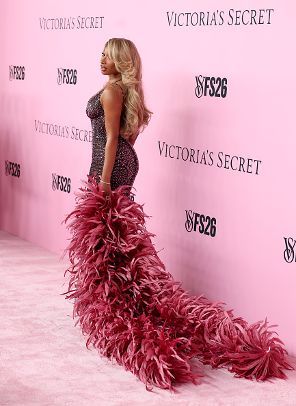 Megan Thee Stallion held a long, oversized hot-pink feather boa in her left hand and styled it with Amina Muaddi “Gilda” black sandals adorned with crystal-encrusted straps