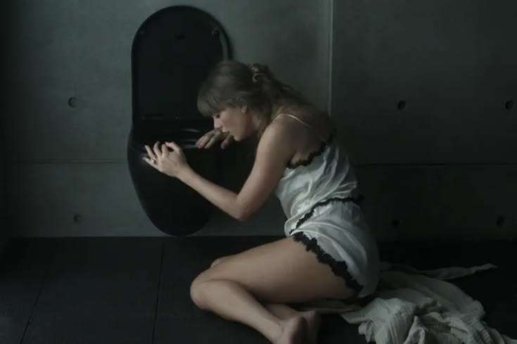 Taylor Swift appeared in her “Patient Zero” music video dressed in an ivory Dôen silk-satin pajama set, including the “Loure” top and “Iona” shorts, each detailed with black lace trim along the edges.